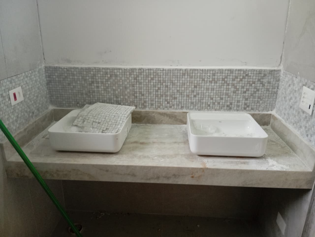 Bancada de banheiro com duas cubas de apoio brancas e pastilhas na casa 6 do Condomínio Enseada 2, Praia da Baleia, durante os acabamentos