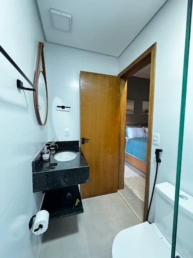 Banheiro do Palulu Flat com bancada preta, espelho e fechamento de vidro