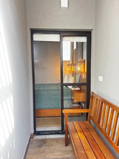 Trecho de circulação do Palulu Flat com banco de madeira e porta de vidro