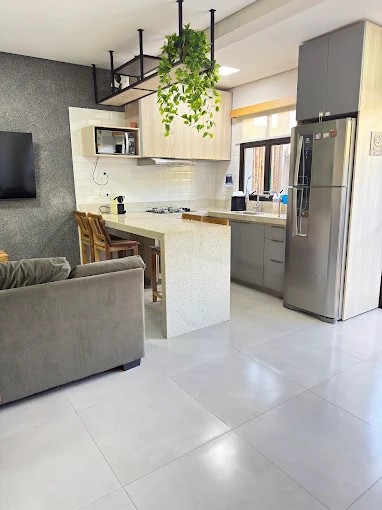 Ambiente integrado de um flat com bancada de cozinha, piso claro e área de estar