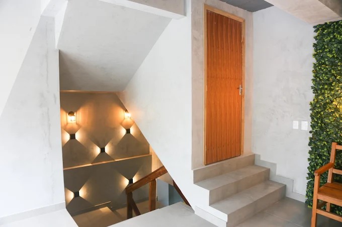 Acesso interno do Palulu Flat com escadas, revestimentos e porta de madeira