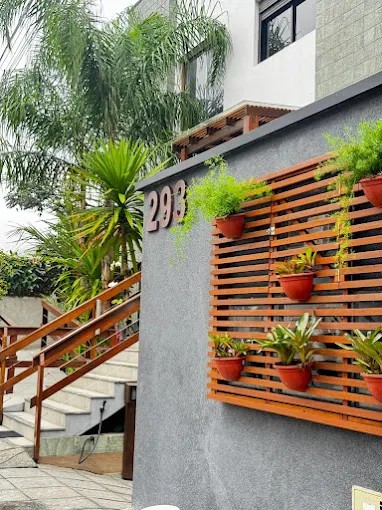 Identificação 293 na fachada do Palulu Flat, com painel de madeira e vasos
