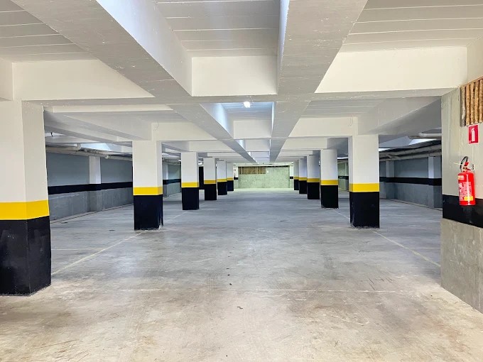 Garagem no subsolo do Palulu Flat com pilares, iluminação e faixas de sinalização
