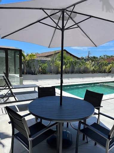 Área de convivência junto à piscina do Palulu Flat com mesa e ombrelone