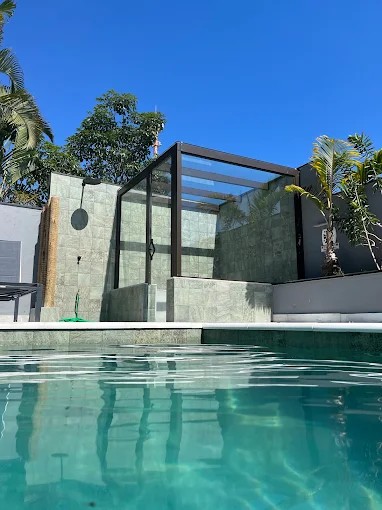 Detalhe da piscina do Palulu Flat com borda revestida e estrutura da área externa ao fundo