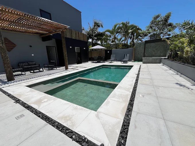 Piscina e área de lazer do Palulu Flat em vista ampla, com bordas e piso do entorno
