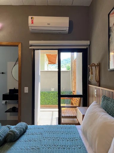 Quarto do Palulu Flat com porta de vidro voltada para o pátio e piso revestido