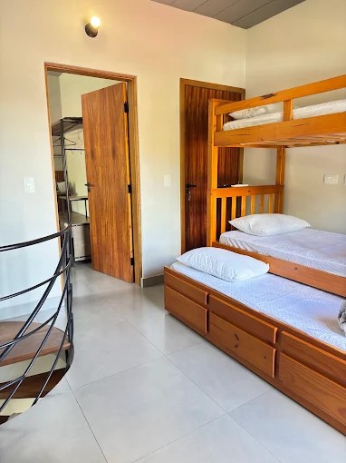 Quarto do Palulu Flat com beliche de madeira e acesso ao banheiro