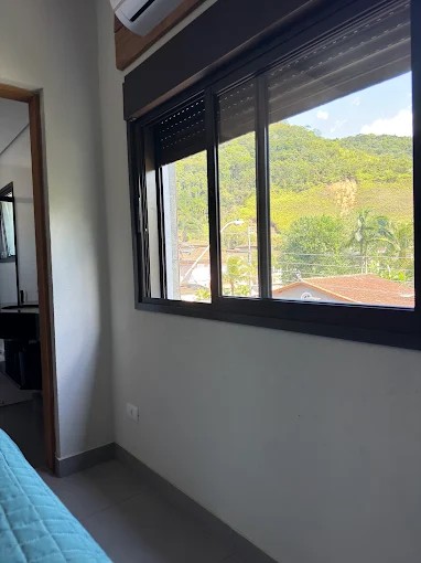 Janela e piso de um quarto do Palulu Flat, com vista para a vegetação de Juquehy