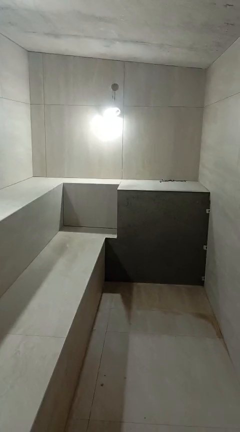 Interior da sauna da academia e sala de jogos do Condomínio Enseada 2, com bancos e paredes revestidos